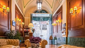 A lobby with leather sofas, a coffee table with a vase, and a chandelier.