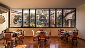 Comedor con un ventanal grande, suelo de madera y sillas tapizadas en rojo.