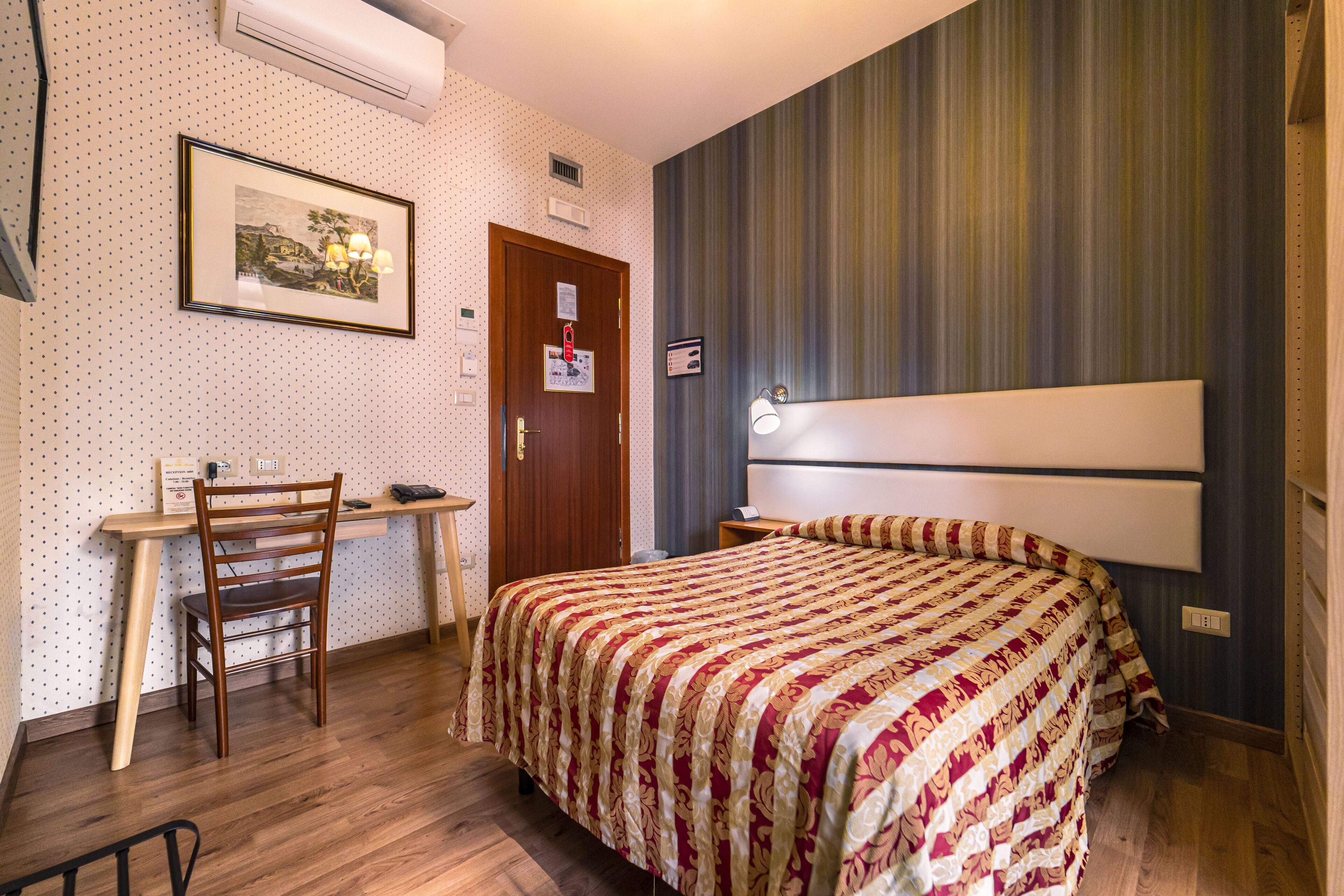 A bedroom with a bed, a desk, and a chair.