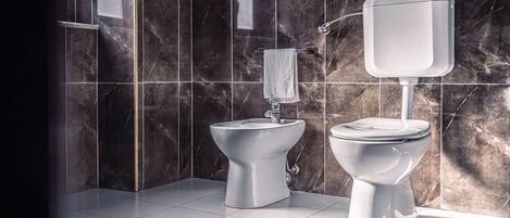 A modern bathroom with a bidet, toilet, and marble tiles.