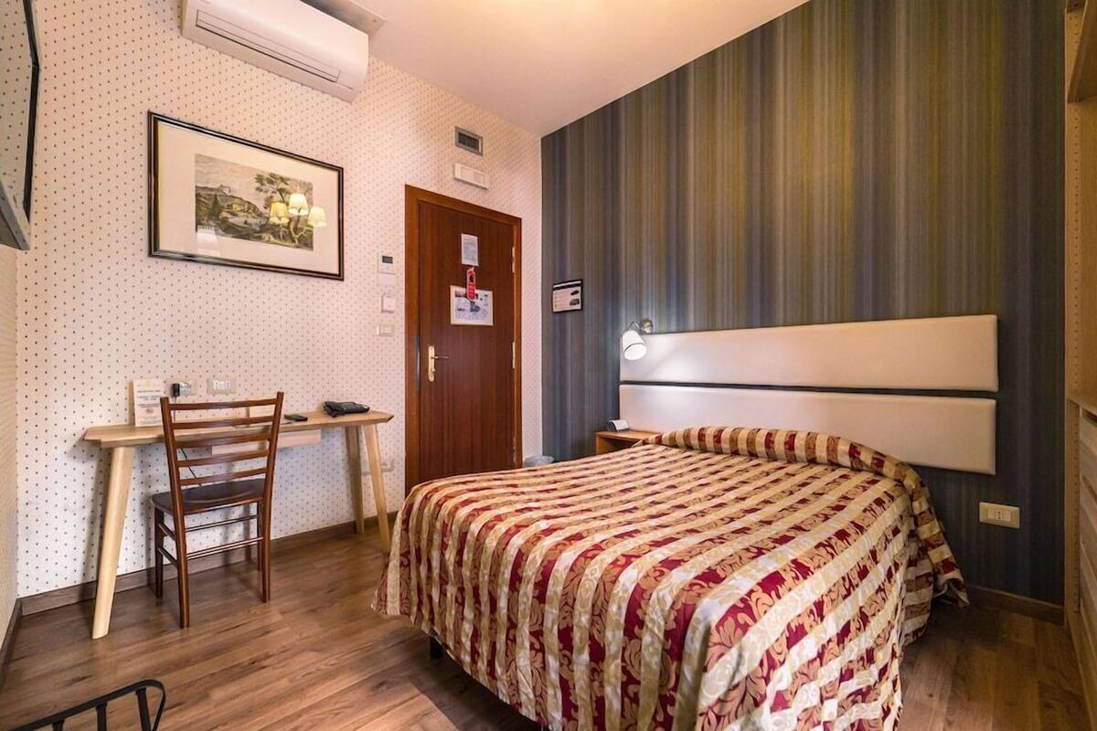 A bedroom with a bed, a desk, and a chair.