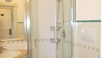 A bathroom with a glass-enclosed shower, a toilet, and a sink.