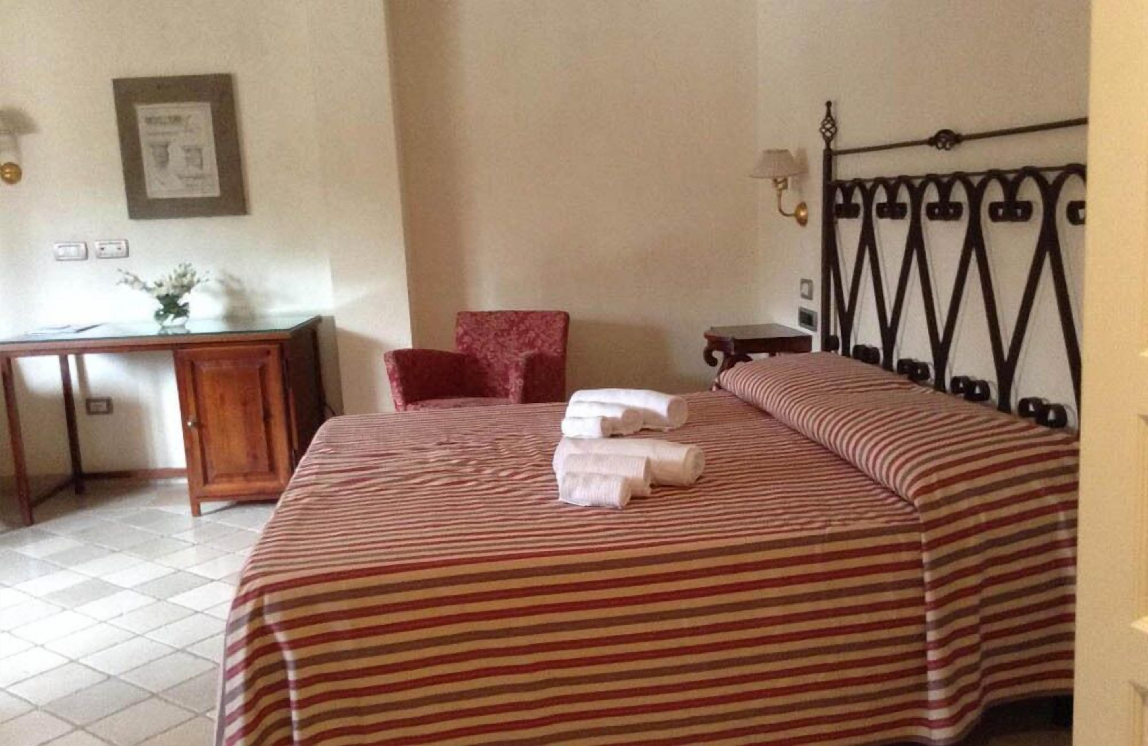 A hotel room with a bed, a desk, a chair, and a nightstand.