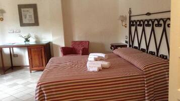 Una habitación de hotel con cama, escritorio, silla y mesita de noche.