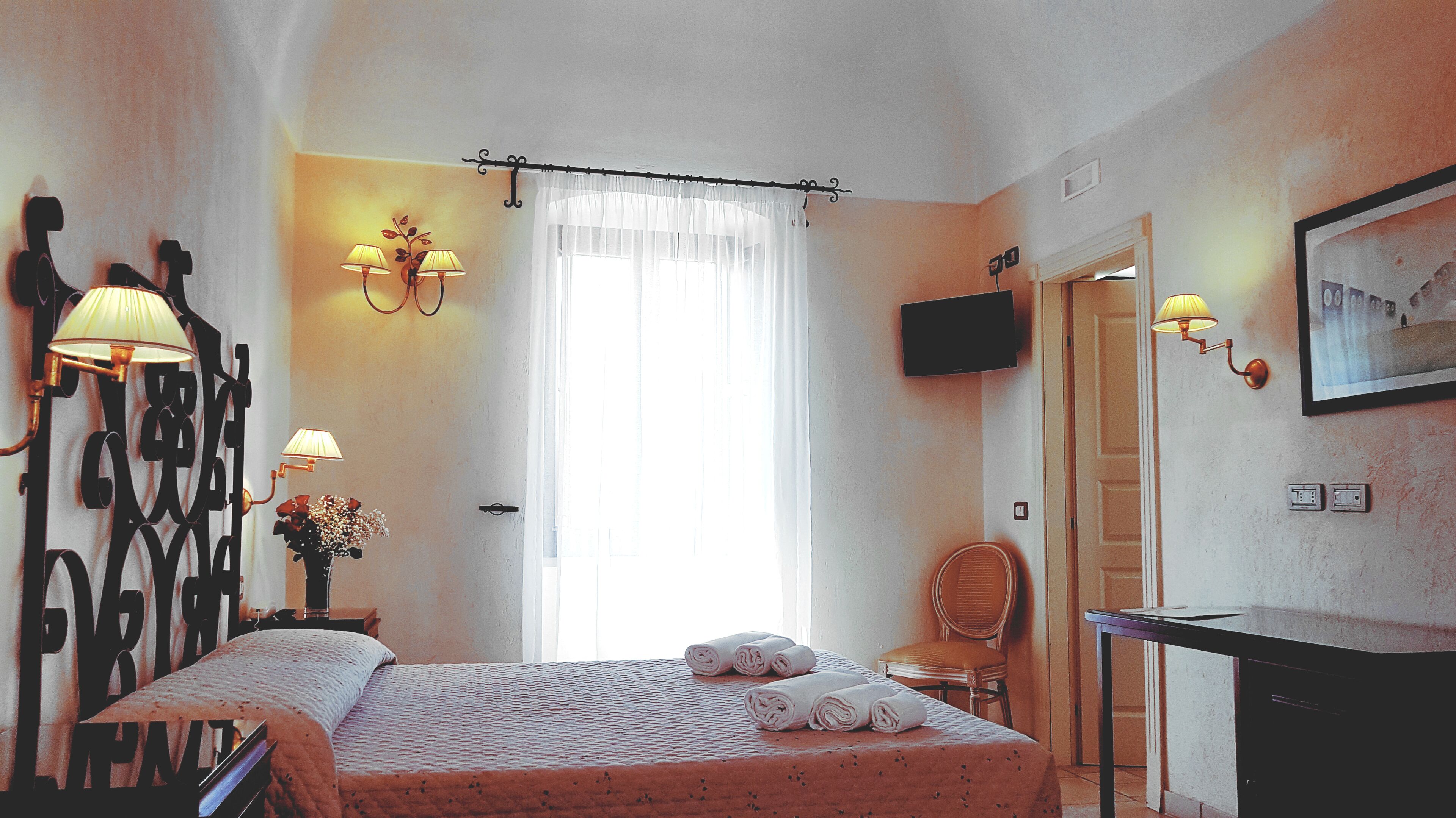 Une chambre d’hôtel avec un lit, une chaise, un bureau et un téléviseur.