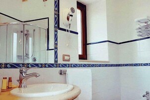 Un baño con lavamanos, espejo y un secador de pelo sujeto a la pared.