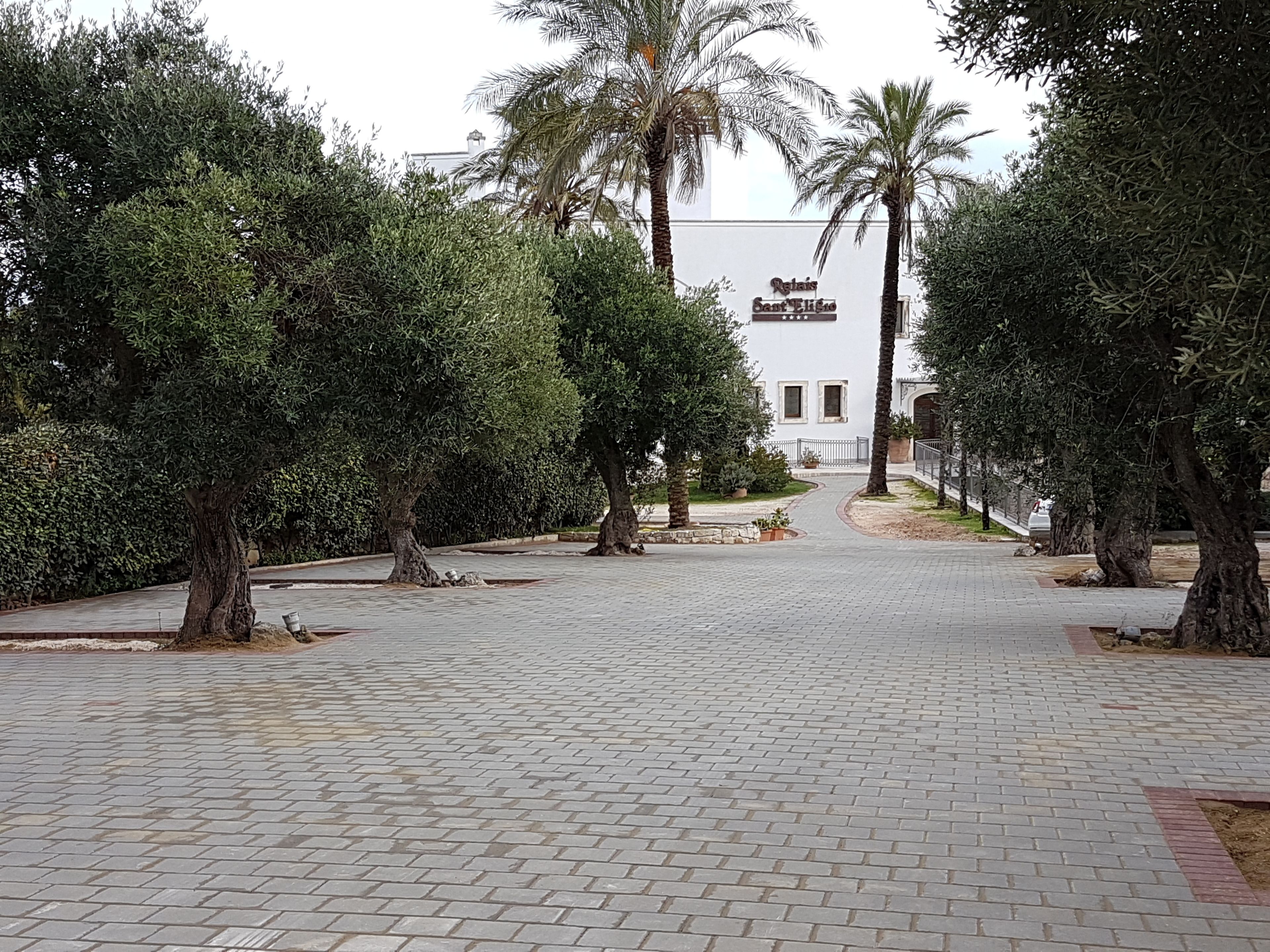 A paved pathway leading to a building with a sign reading "Regal Sant'Elige."