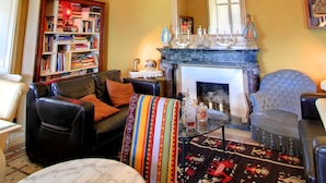 A living room with a fireplace, a chandelier, a bookshelf, and a patterned rug.