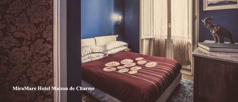 A bedroom with a bed, a nightstand, a window with curtains, and a wall-mounted picture.