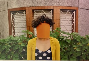 Una persona in piedi di fronte a un edificio con una finestra e un siepe.