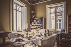 A dining area with a table set for a meal, surrounded by wicker chairs and a leather sofa. - Miramare Cagliari Hotel Museo (Cagliari)