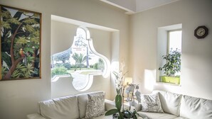 Un salon avec un canapé blanc, une table basse en verre et un tableau représentant un arbre.