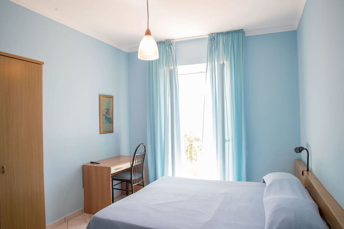 A bedroom with a bed, a desk, and a chair.
