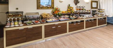 Mesa de buffet con diferentes alimentos y un reloj en la pared.