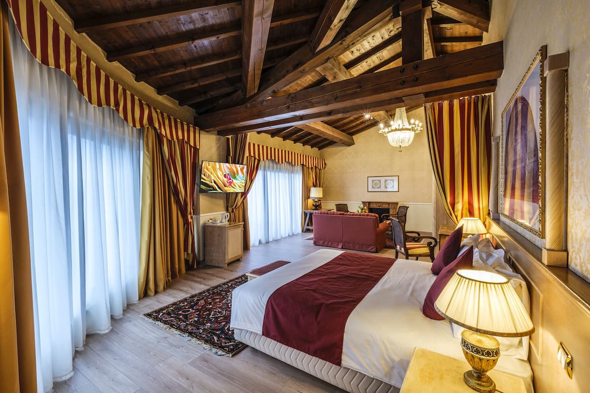 Una habitación de hotel con una cama grande, un escritorio, una silla y una araña.