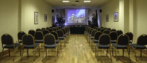 A conference room with rows of chairs facing a projection screen.