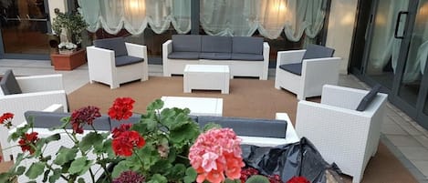 An outdoor seating area with wicker furniture and potted plants.