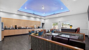 A modern hotel lobby with a kitchen area, seating arrangements, and a view of the outdoors. - Sonesta Essential Hotel Houston-I-45 Spring (Houston)