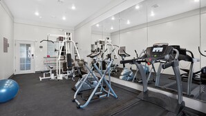 A gym with exercise equipment, a mirrored wall, and a blue exercise ball. - Sonesta Essential Hotel Houston-I-45 Spring (Houston)