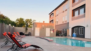 A pool area with lounge chairs, a building with multiple floors, and a sign indicating an emergency dial. - Sonesta Essential Hotel Houston-I-45 Spring (Houston)