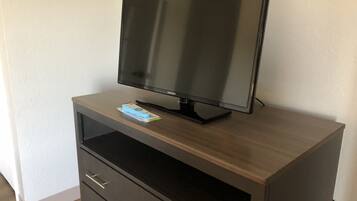 A Samsung TV on a wooden TV stand with a remote control.
