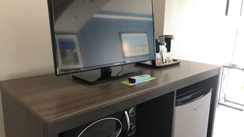 A Samsung TV on a wooden desk with a coffee machine and a remote control.