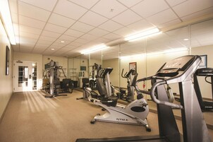 A gym with cardio machines, weight equipment, and a mirrored wall.
