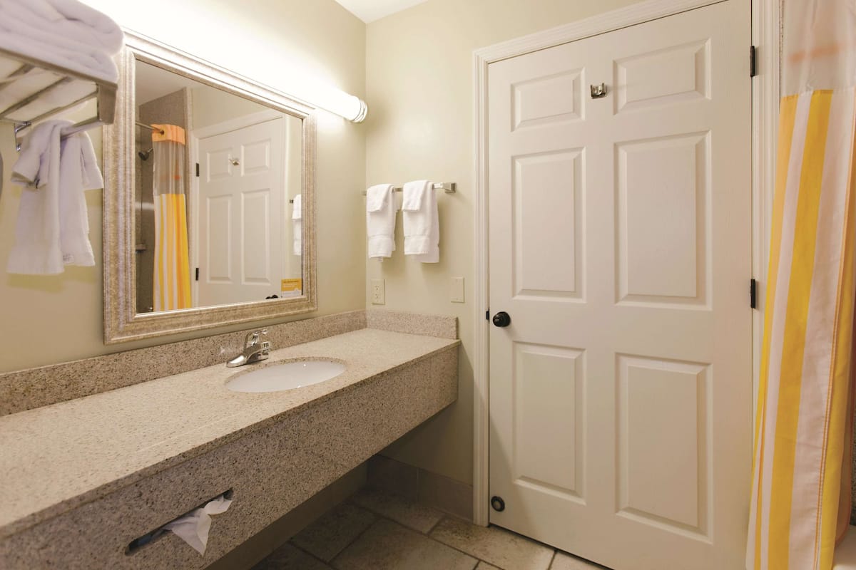 A bathroom with a sink, mirror, and towel rack.