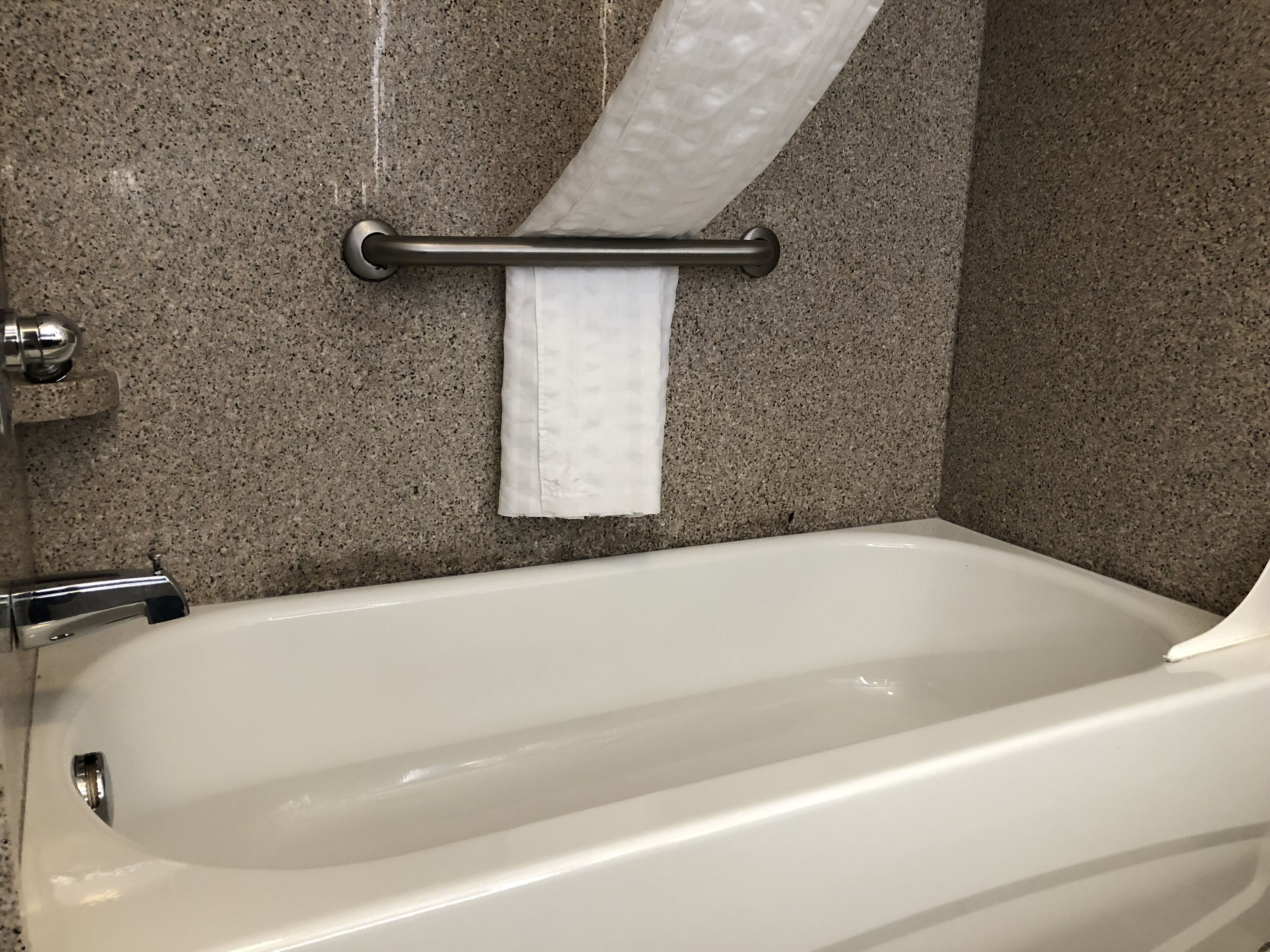 Un baño con bañera, toallero y cortina de ducha.