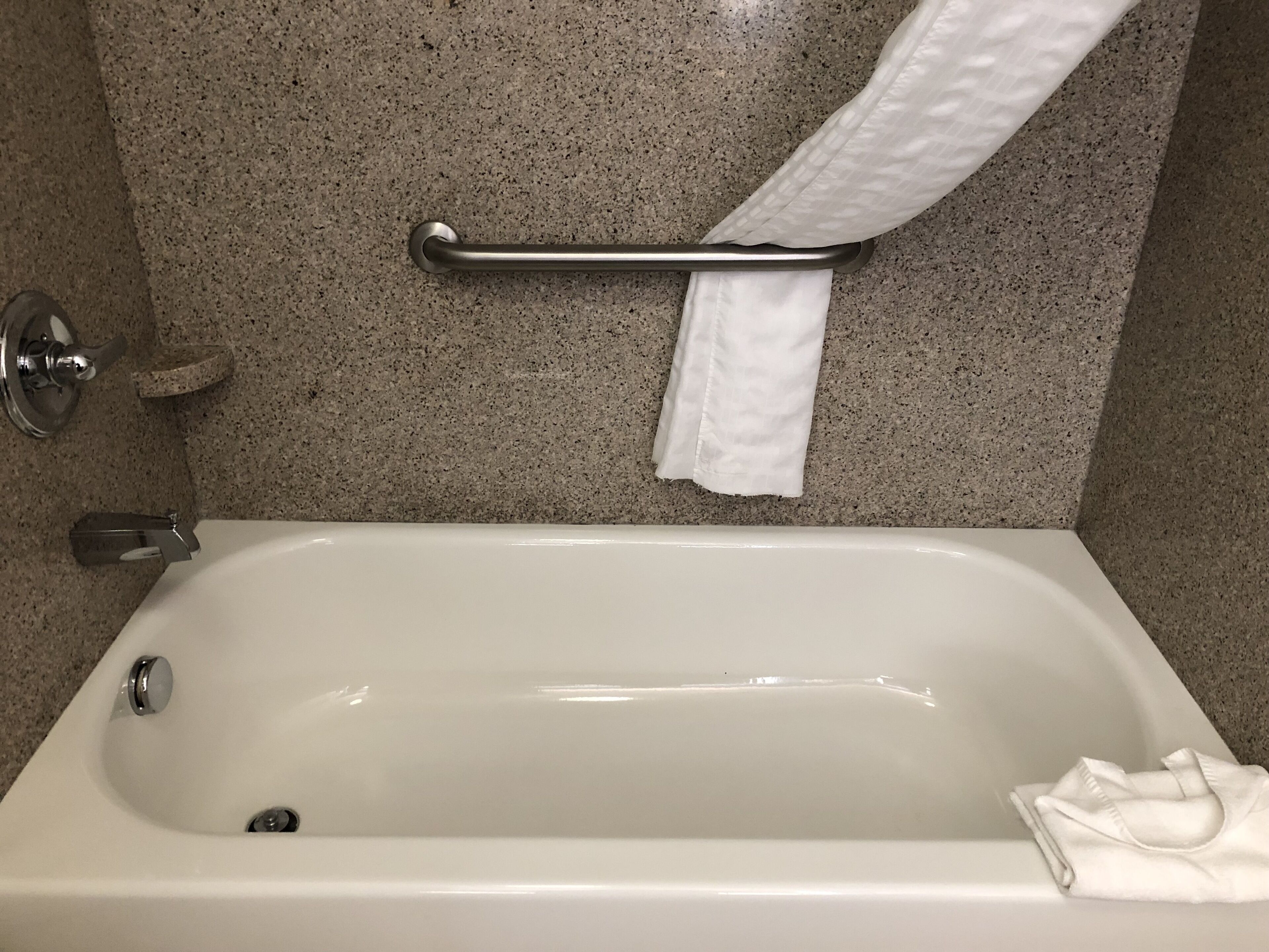 A bathroom with a bathtub, a towel rack, and a paper towel dispenser.