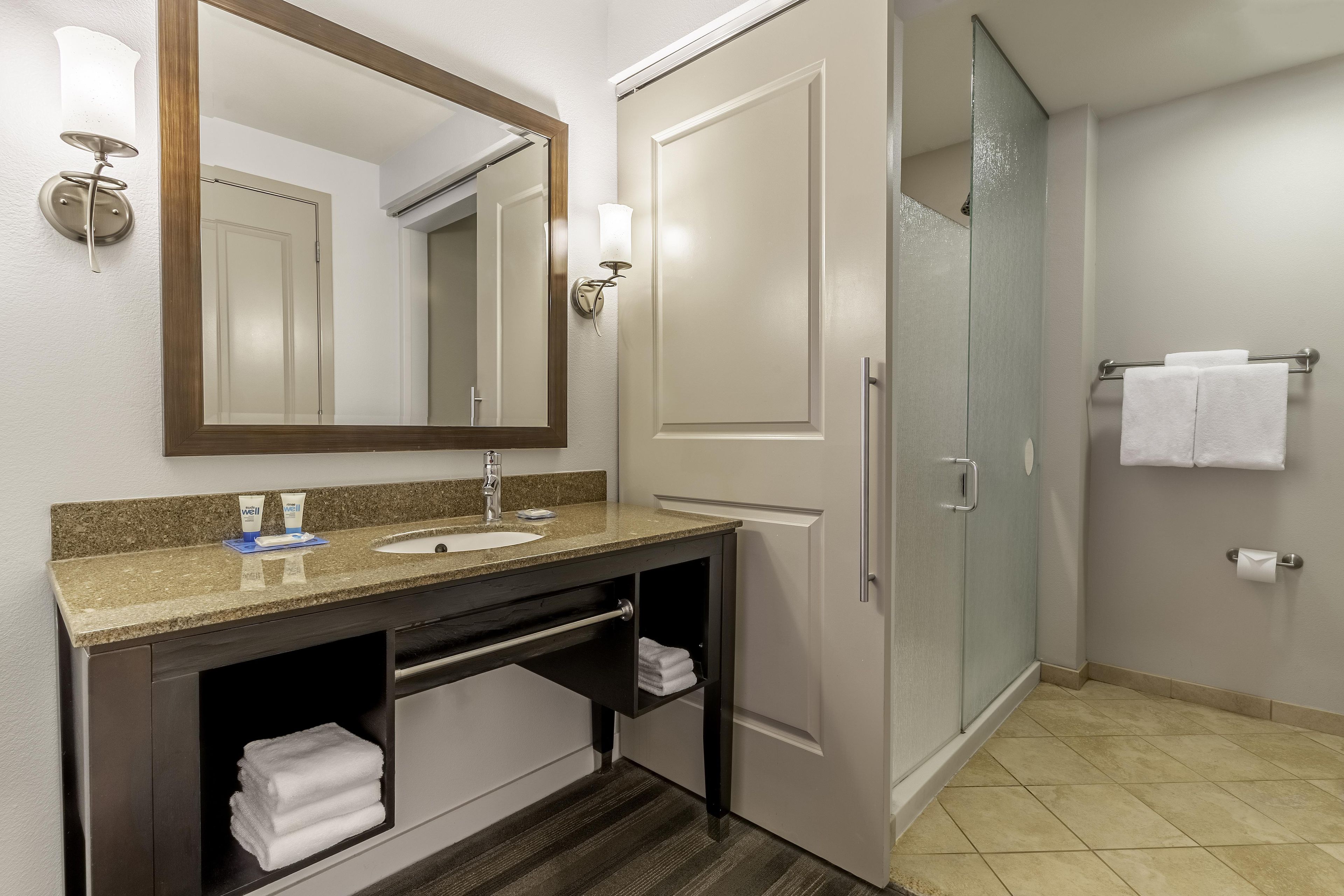 Une salle de bain équipée d’un lavabo, d’un miroir, d’un porte-serviettes et d’une cabine de douche en verre.