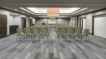 A conference room with rows of chairs, a large screen, and a ceiling light.