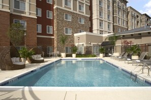 A swimming pool with lounge chairs and a brick building in the background. - HYATT house Sterling/Dulles Airport-North (Sterling)