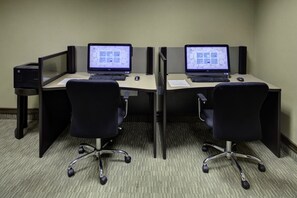 Una oficina en cubículo con dos escritorios, cada uno con una computadora y un teclado.