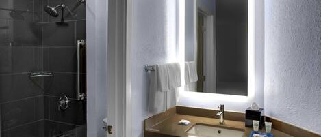 A bathroom with a bathtub, a shower, and a sink with a mirror above it.