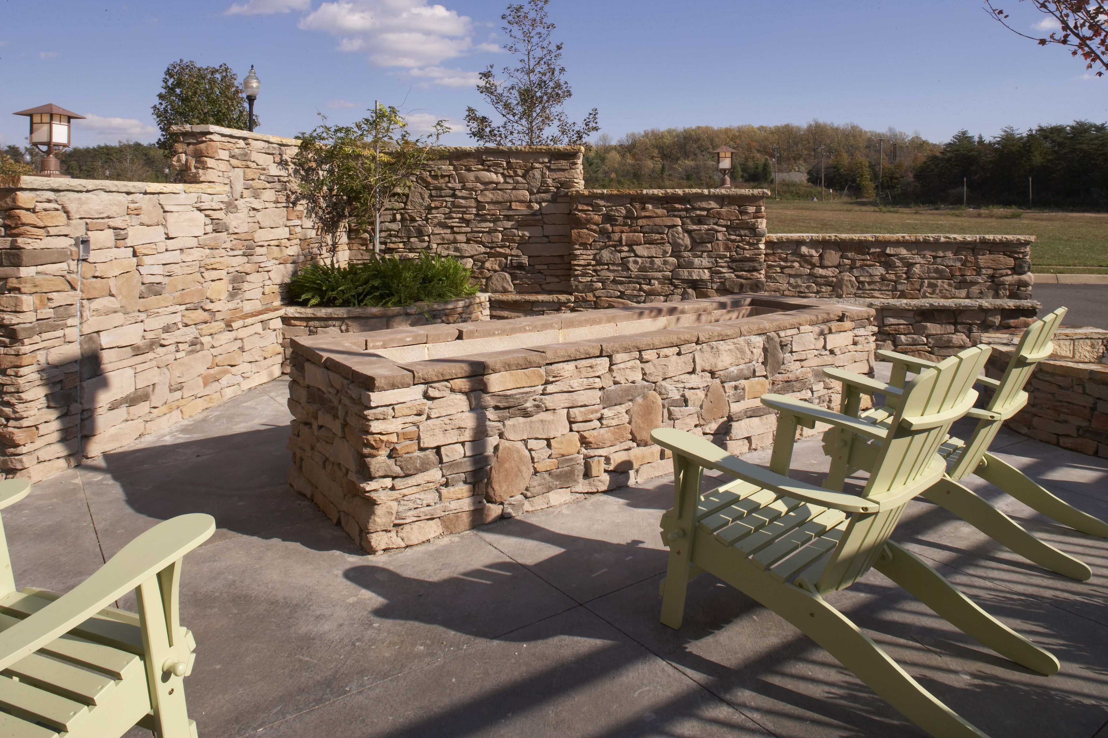 Un patio con paredes de piedra, mobiliario exterior y vistas del paisaje circundante.