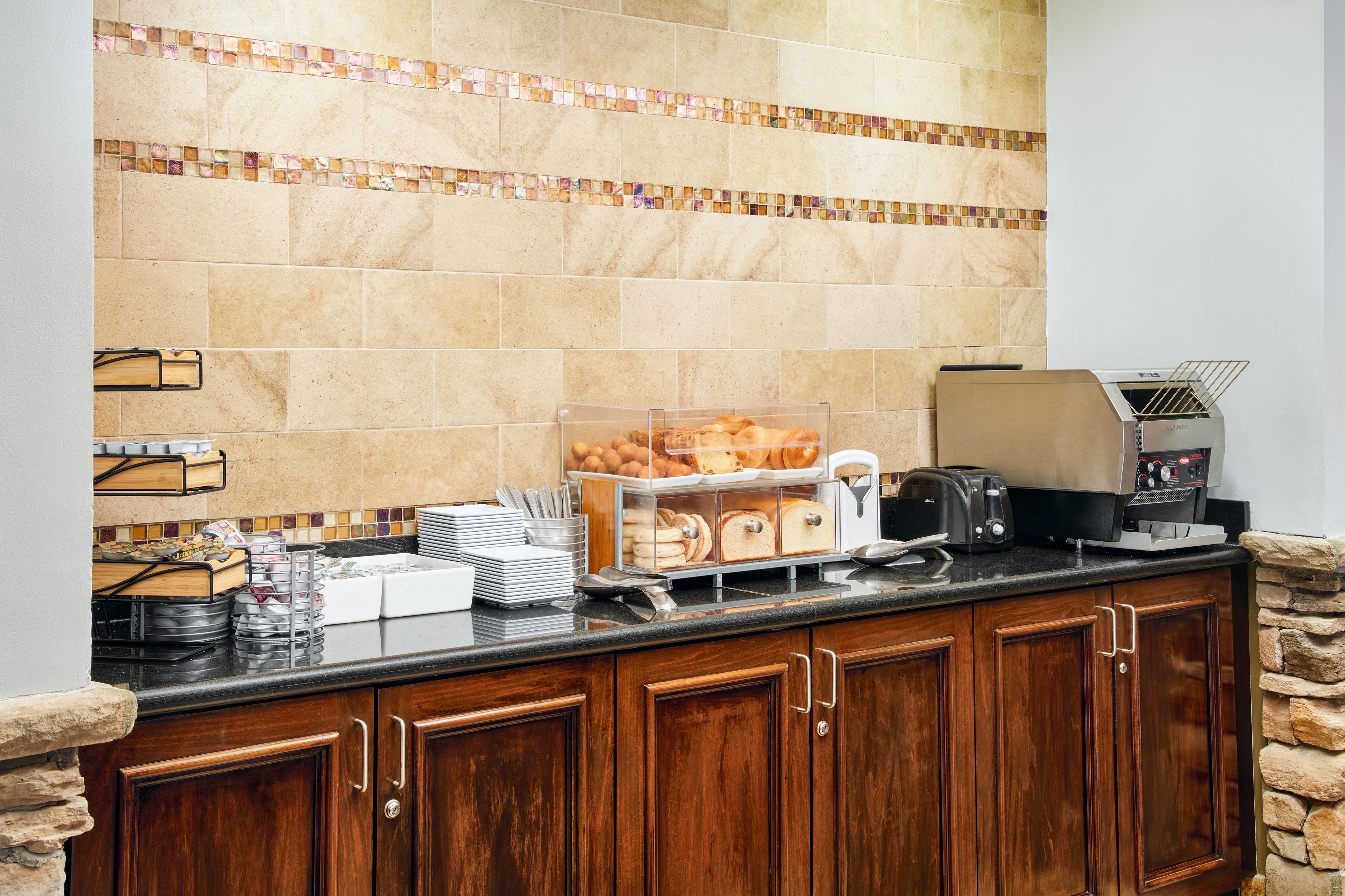 A breakfast bar with a coffee maker, toaster, and bread display.