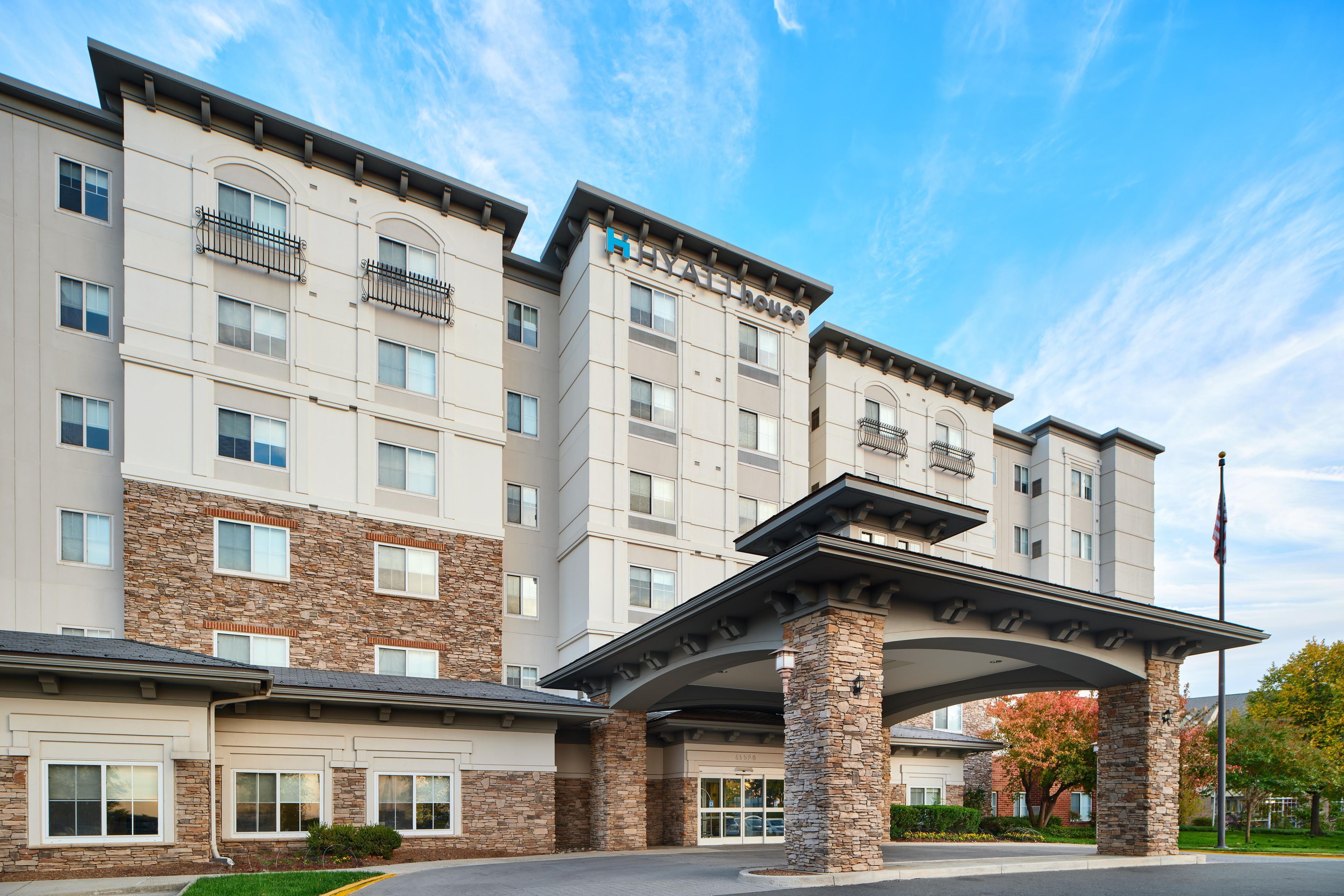 A multi-story hotel with a stone facade, multiple balconies, and a covered entrance.