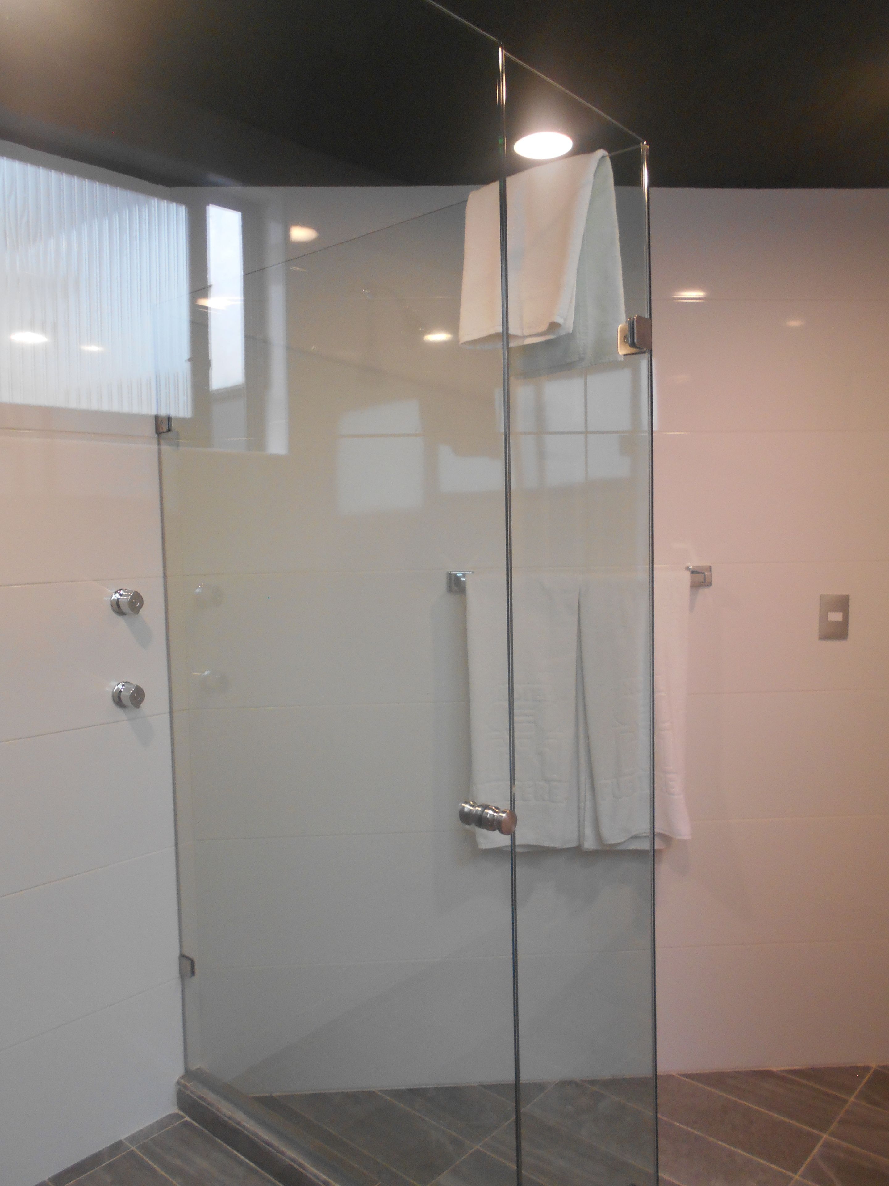 A glass-enclosed shower with a white towel hanging on the wall.