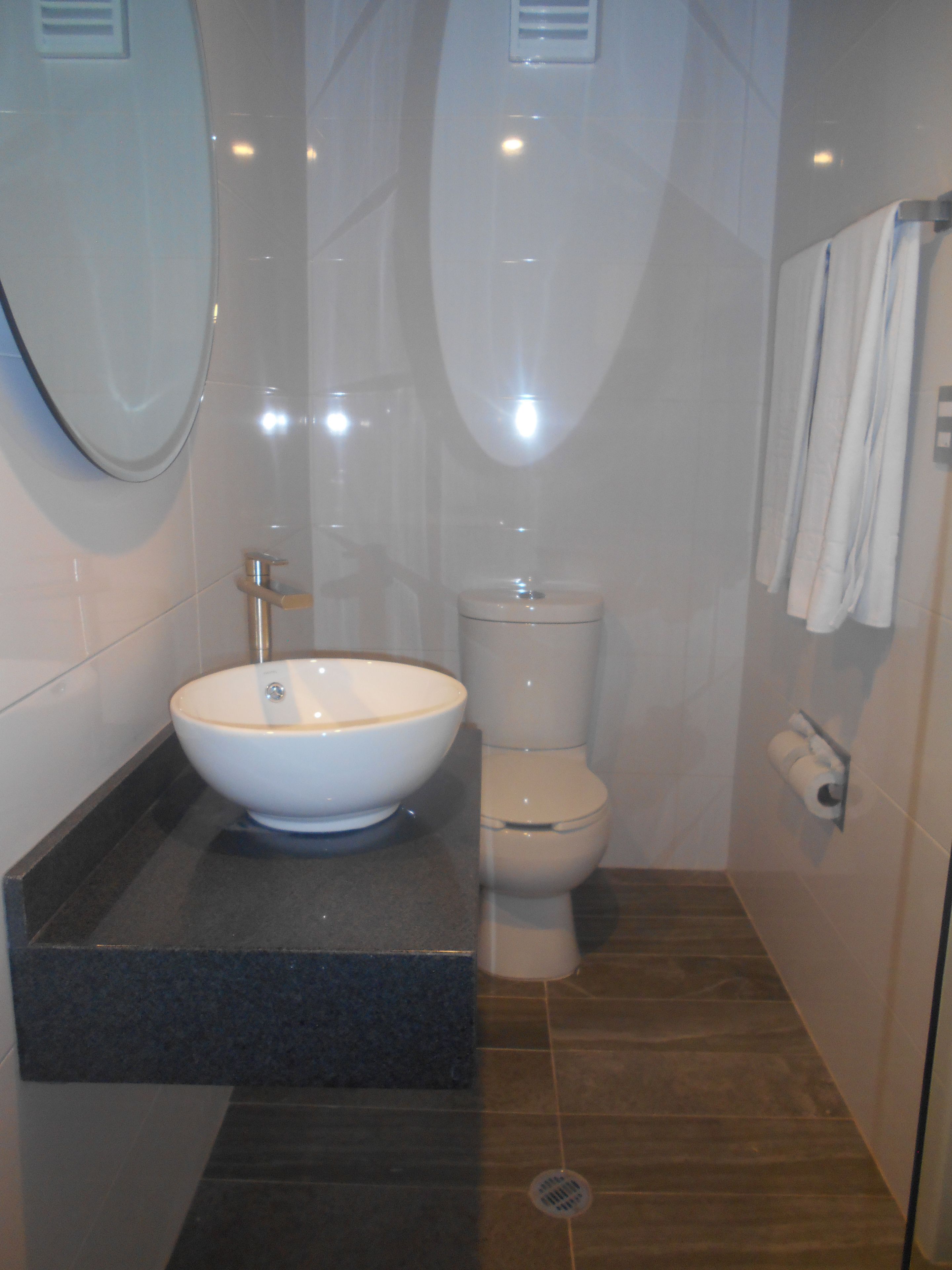 Un baño moderno con un lavamanos, inodoro y un espejo grande.