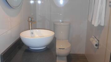 Un baño moderno con un lavamanos, inodoro y un espejo grande.
