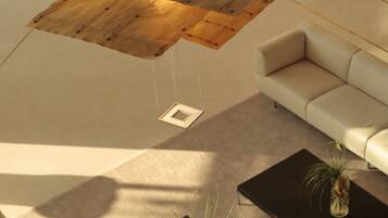 A modern living room with a sectional sofa, two black coffee tables with vases, and a wooden ceiling feature.