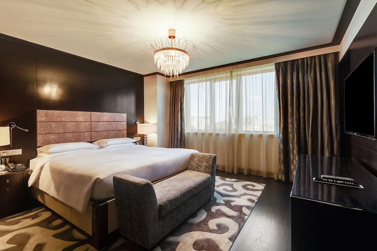 Ein modernes Hotelzimmer mit einem großen Bett, einem Flachbildfernseher und einer Kronleuchter.