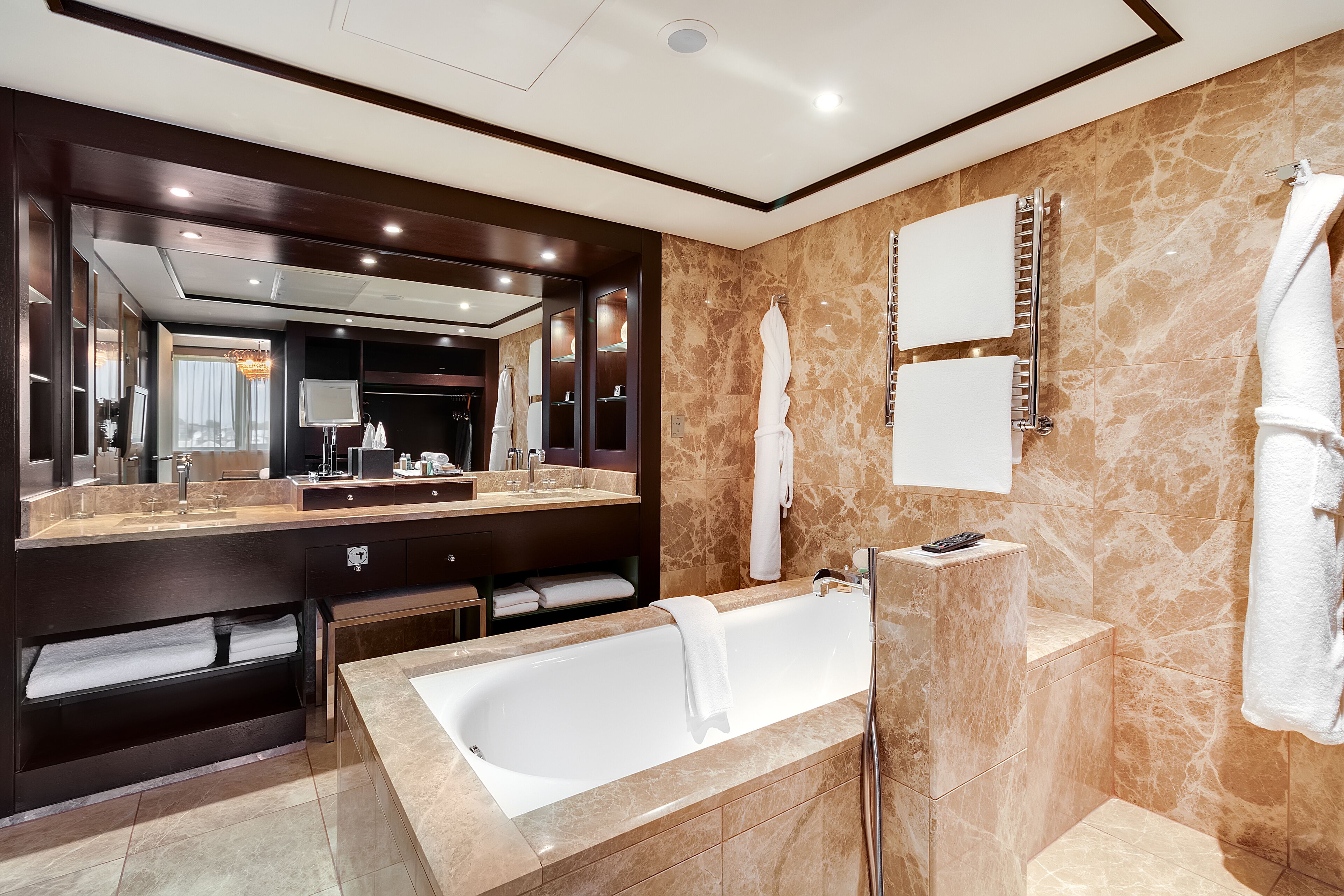 A modern bathroom with a large bathtub, a vanity with a mirror, and a towel rack.