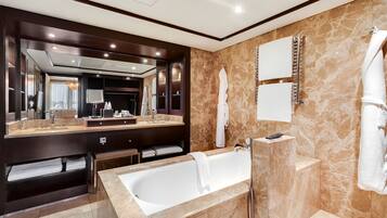 A modern bathroom with a large bathtub, a vanity with a mirror, and a towel rack.