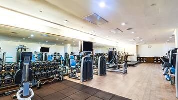 Ein Fitnessstudio mit unterschiedlichen Trainingsgeräten, Spiegeln und einer Wanduhr.