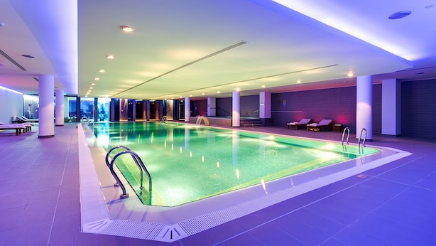 An indoor swimming pool with clear water, surrounded by lounge chairs and a modern ceiling design. - Hyatt Regency Kyiv (Kyiv)