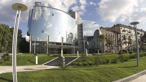 A modern hotel with a glass facade, a central courtyard, and a traditional building in the background. - Hyatt Regency Kyiv (Kyiv)