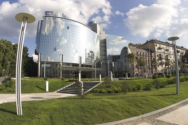 A modern hotel with a glass facade, a central courtyard, and a traditional building in the background. - Hyatt Regency Kyiv (Kyiv)
