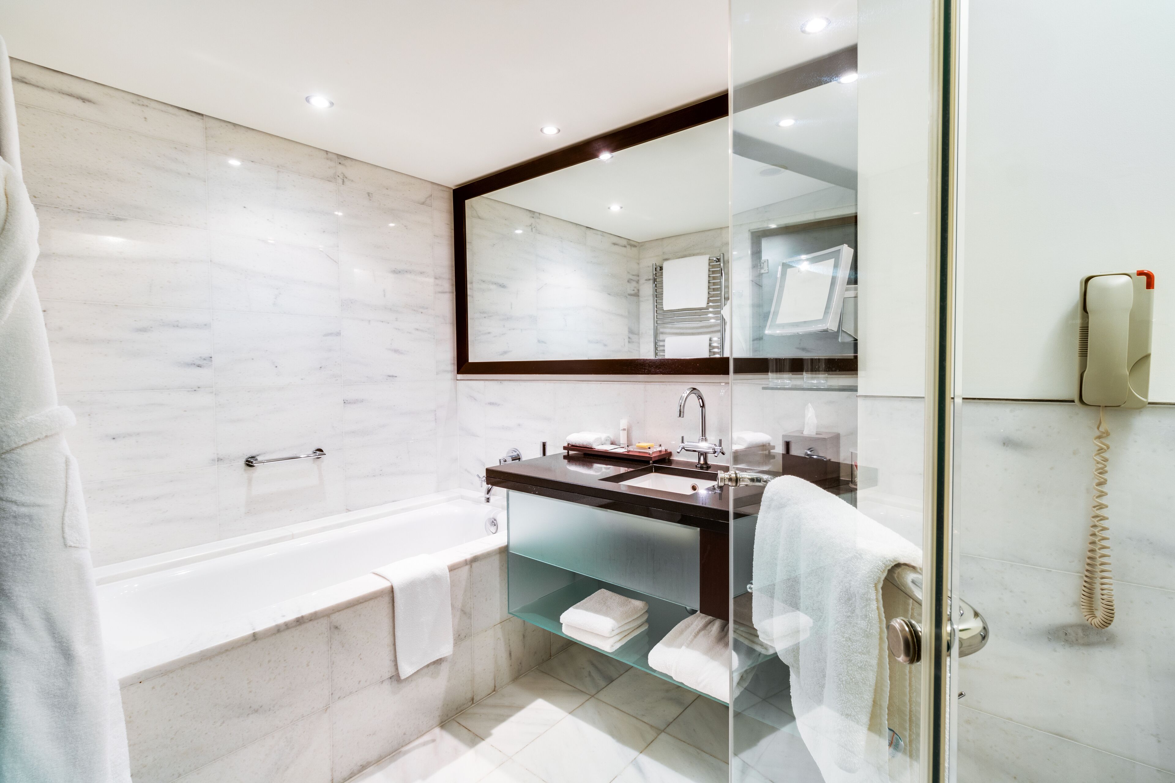A modern bathroom with a glass-enclosed shower, a bathtub, and a vanity with a mirror.